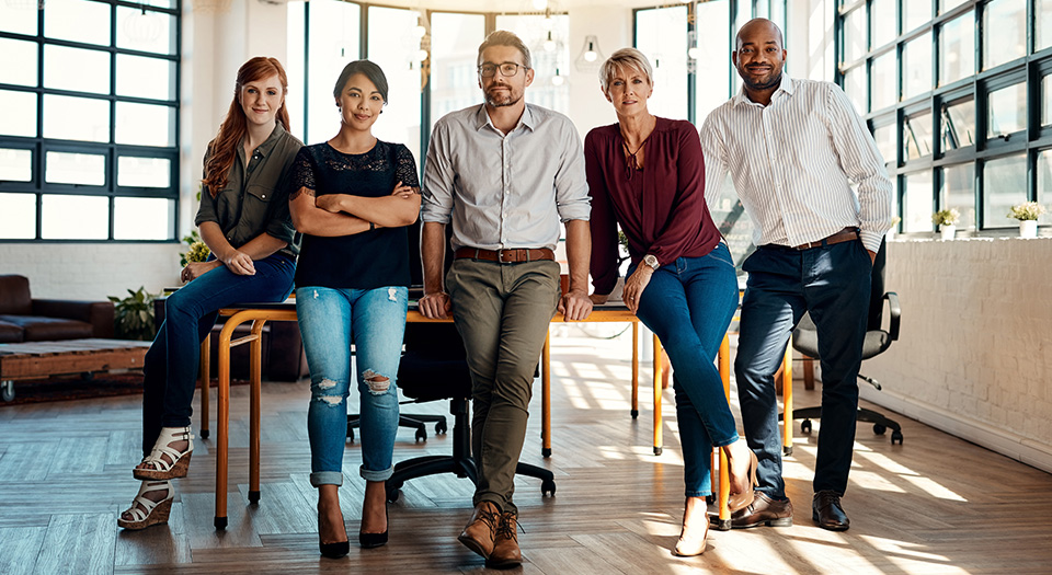 Five people leaning on a table looking at the camera