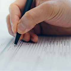 hand with pen filling out a form